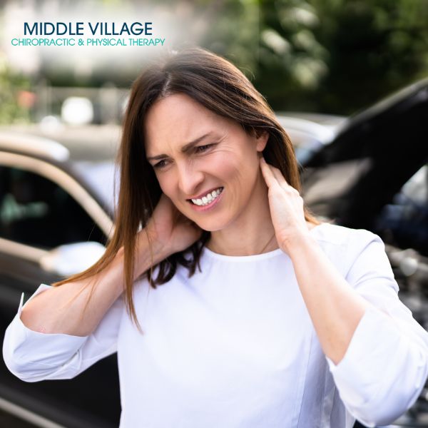 A woman in a white shirt stands outdoors, clutching her neck in discomfort. In the background, a car with an open hood hints at the challenges of her day. Perhaps a visit to the chiropractor in Corona could ease her pain and turn things around.